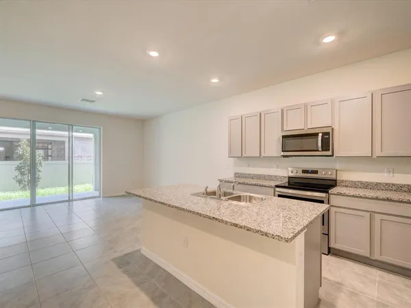 a kitchen with granite countertop a stove sink and microwave