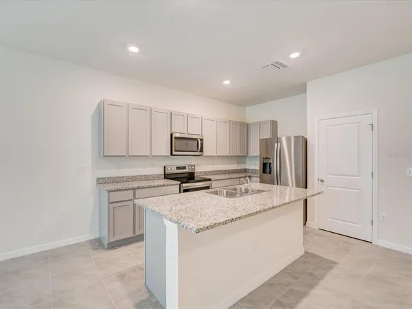 a kitchen that has a refrigerator a stove and white cabinets