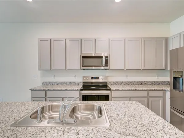 a kitchen with granite countertop a sink a stove and a microwave