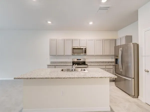 a kitchen with stainless steel appliances granite countertop a refrigerator a stove a sink and a granite counter tops