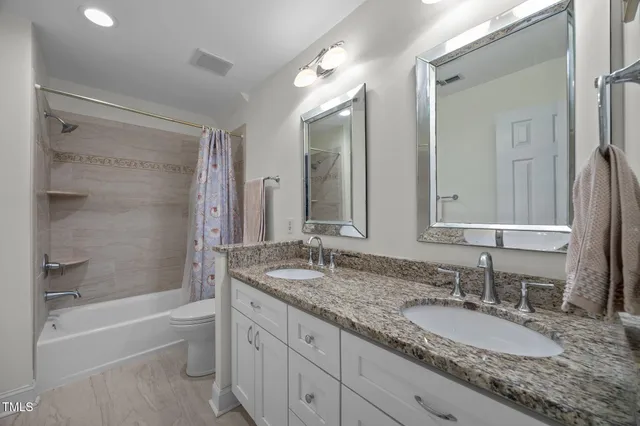 a bathroom with a granite countertop double vanity sink and a mirror
