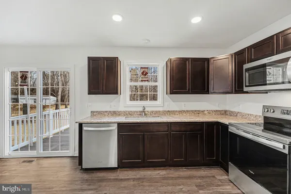 a kitchen with stainless steel appliances granite countertop a sink and a stove top oven with wooden floor