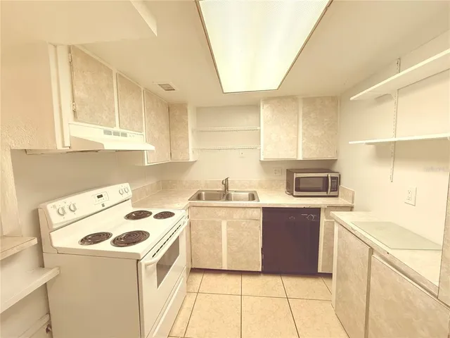 a kitchen with a sink a stove top oven and white cabinets