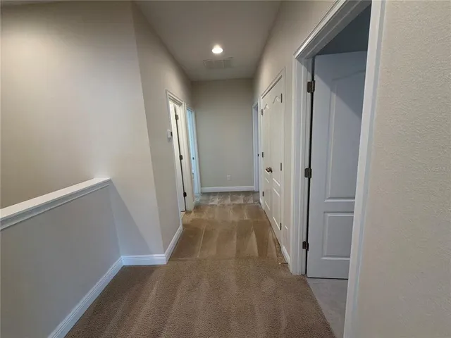 a view of a hallway with wooden floor and closet