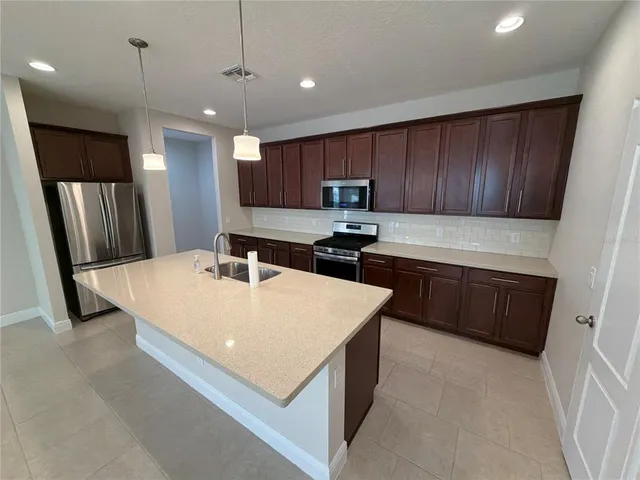 a large kitchen with stainless steel appliances granite countertop a sink a stove and a refrigerator