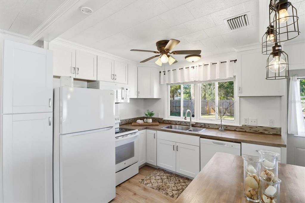 1050 North Midiron Point Crystal River, FL 34429 - Photo 15 of 57 a kitchen with stainless steel appliances granite countertop a refrigerator a sink dishwasher a stove and white cabinets with wooden floor