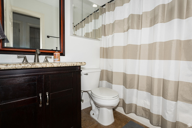 7797 North Windhover Road Eagle Mountain, UT 84005 - Photo 25 of 33 Bathroom featuring a dark wood-finish vanity with a stone countertop, an undermount sink, and a framed mirror