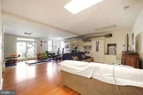 a large bedroom with wooden floor and large windows