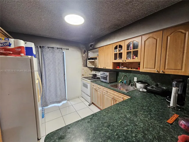 a kitchen with stainless steel appliances granite countertop a refrigerator a stove and a sink