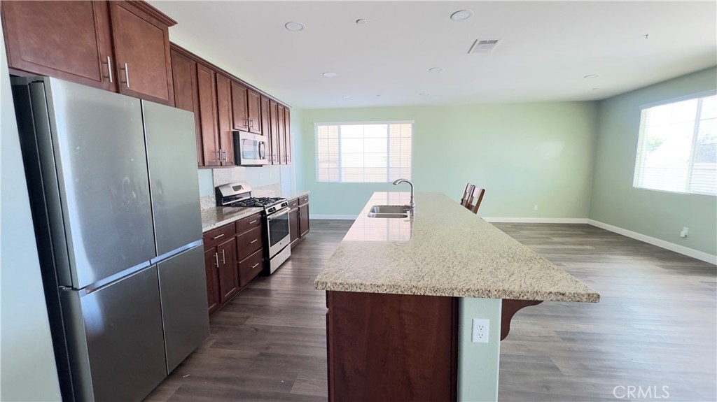 3687 White Ash Road San Bernardino, CA 92407 - Photo 13 of 29 a kitchen with stainless steel appliances granite countertop a refrigerator a sink a stove a dining table and chairs