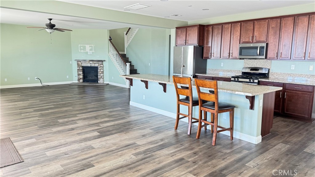 3687 White Ash Road San Bernardino, CA 92407 - Photo 9 of 29 a open kitchen with stainless steel appliances granite countertop a stove top oven a refrigerator a dining table and chairs with wooden floor
