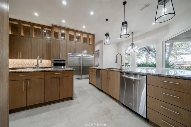 a kitchen with stainless steel appliances kitchen island granite countertop a refrigerator and a sink