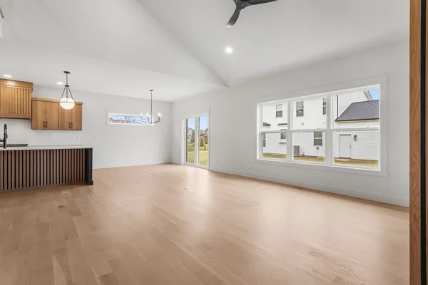 an empty room with a ceiling fan and kitchen view
