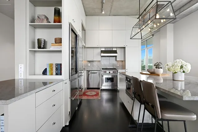 a kitchen with stainless steel appliances granite countertop a white cabinets a sink dishwasher and a stove with wooden floor