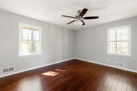 a view of empty room with wooden floor and fan