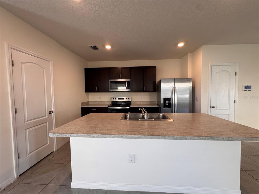 2095 King Ranch Street Kissimmee, FL 34744 - Photo 4 of 17 a kitchen with stainless steel appliances granite countertop a refrigerator a sink a stove a microwave and a refrigerator