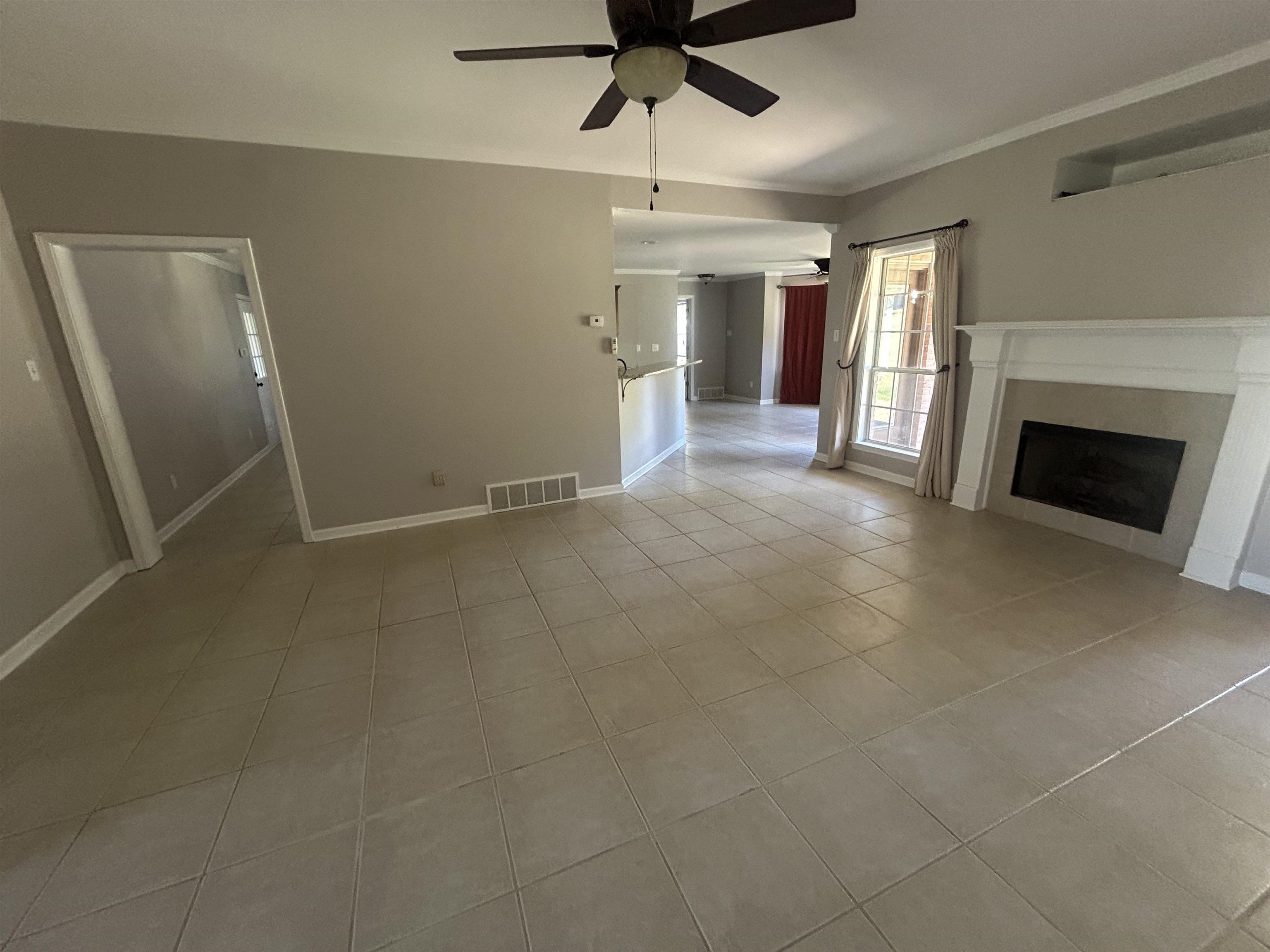 9958 Idaville Road Atoka, TN 38004 - Photo 11 of 20 Unfurnished living room featuring ceiling fan, light tile patterned flooring, a fireplace, and crown molding