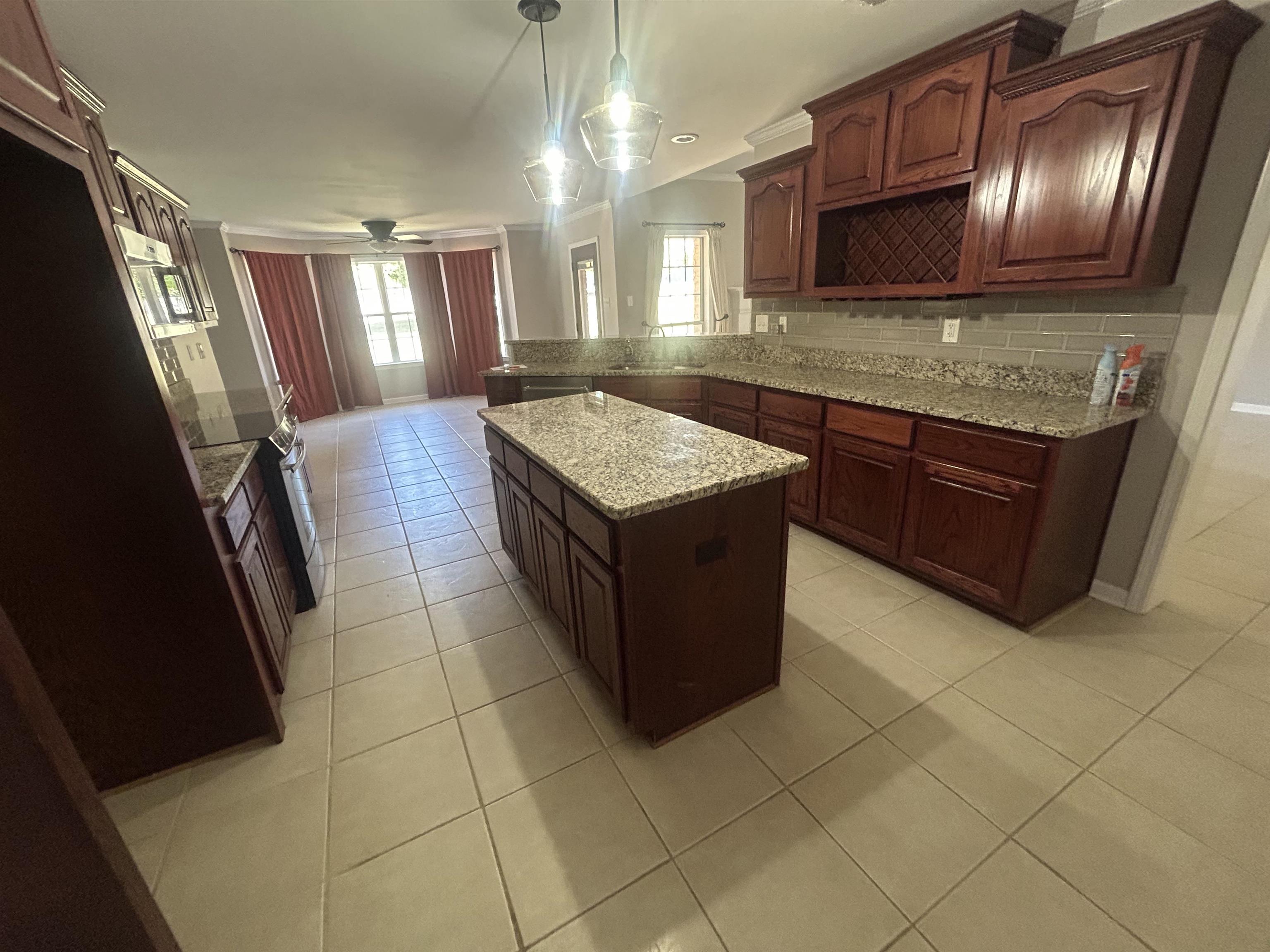9958 Idaville Road Atoka, TN 38004 - Photo 5 of 20 Kitchen featuring light stone countertops, light tile patterned floors, pendant lighting, a kitchen island, and electric range