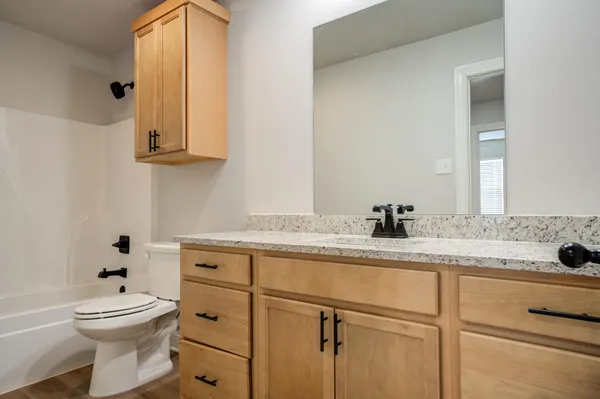 a bathroom with a granite countertop sink a toilet and mirror