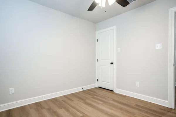 an empty room with a ceiling fan and wooden floor