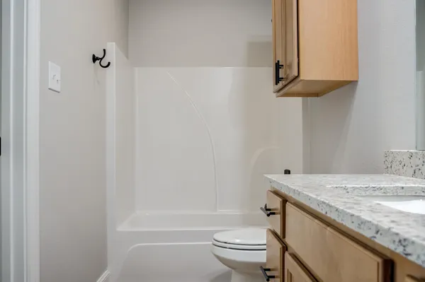 a bathroom with a granite countertop sink a toilet and shower