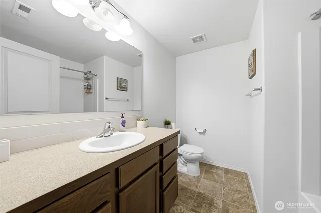 a bathroom with a sink a toilet a mirror and shower