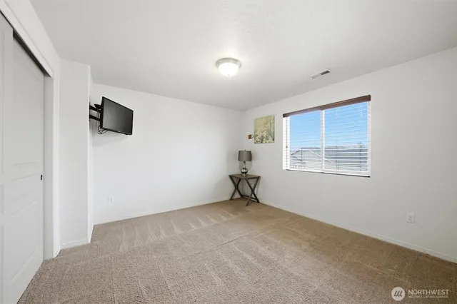 a view of an empty room with wooden floor and windows