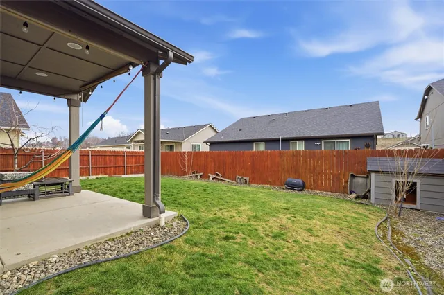 a view of a backyard with couches under an umbrella