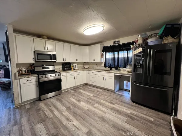a kitchen with granite countertop a refrigerator stove top oven and sink