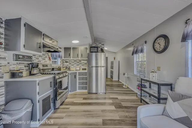 a kitchen with stainless steel appliances granite countertop a refrigerator a stove and white cabinets with wooden floors