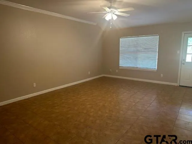 an empty room with a fan & a window