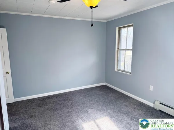 an empty room with windows and chandelier fan