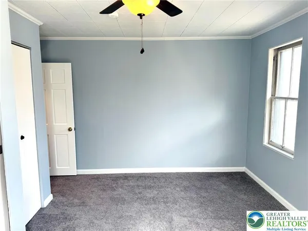 an empty room with a window and a ceiling fan