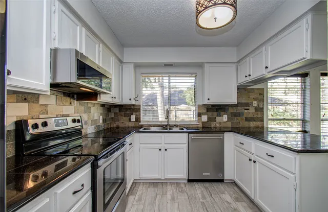 a kitchen with stainless steel appliances a sink a stove and cabinets