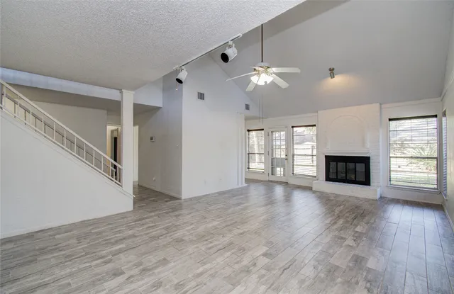 a view of an empty room with wooden floor fireplace and a window