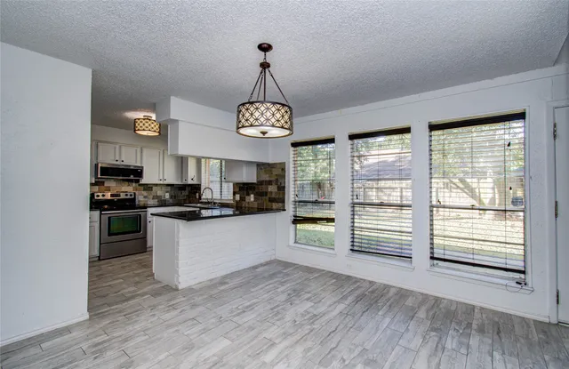 a kitchen with stainless steel appliances granite countertop a stove and a wooden floors