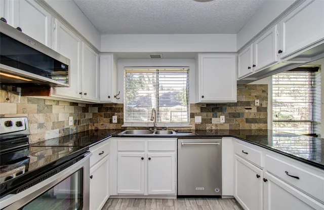 a kitchen with white cabinets and appliances