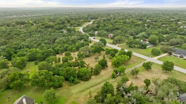 an aerial view of residential houses with outdoor space and trees