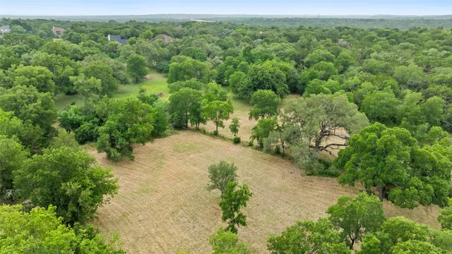 an aerial view of residential houses with outdoor space and trees all around