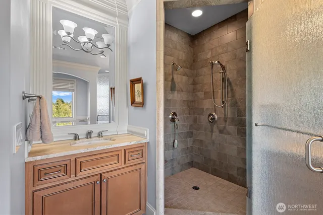 a bathroom with a sink a mirror a glass door a shower and a mirror