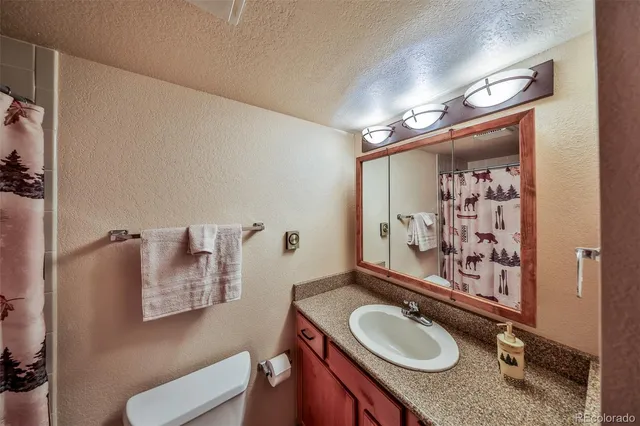 a bathroom with a granite countertop sink mirror vanity and toilet