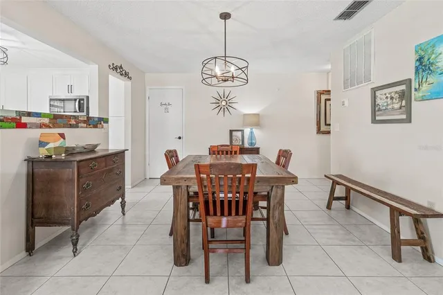 a dining room filled chandelier and kitchen view