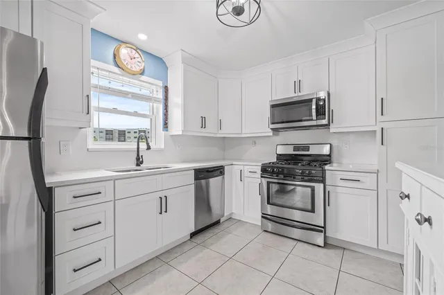 a kitchen with white cabinets appliances and a window