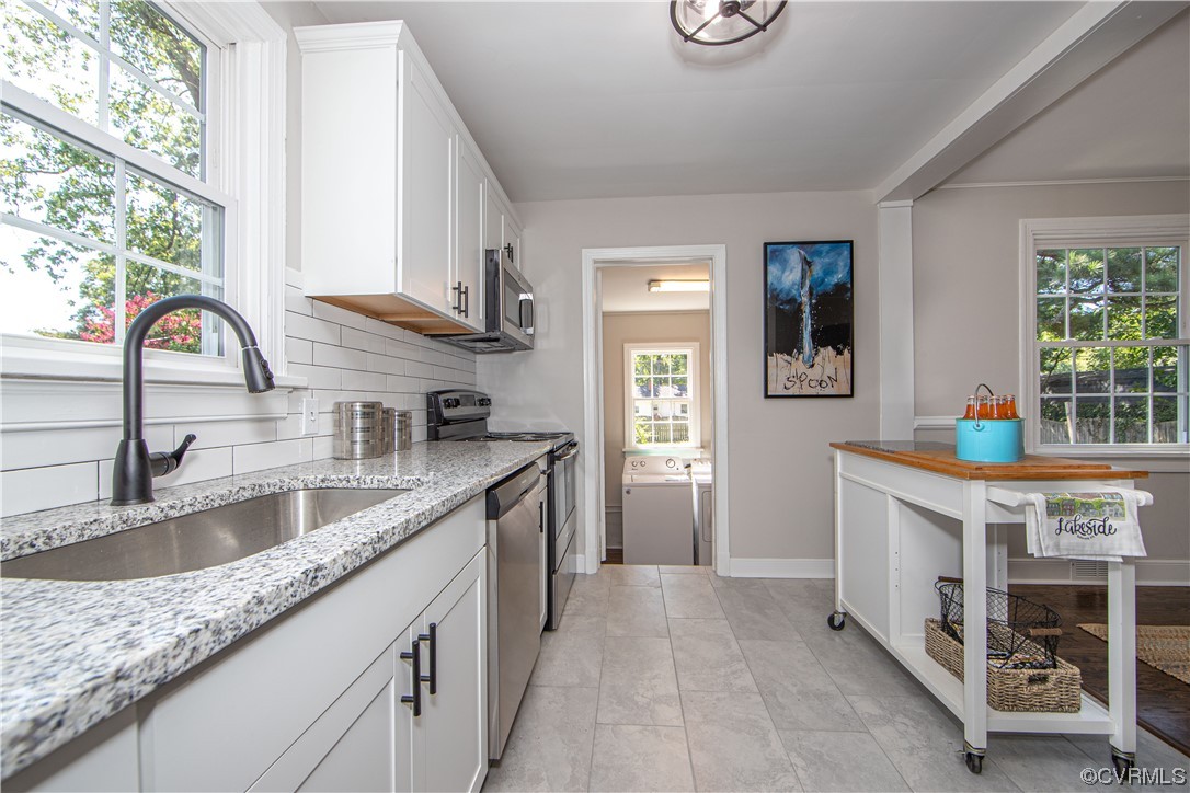 3009 Pinehurst Road Henrico, VA 23228 - Photo 16 of 34 Kitchen with stainless-steel appliances, white cabinetry, tile backsplash, stainless-steel sink with disposal, granite countertops, tile floor, view to the laundry room and into the dining room