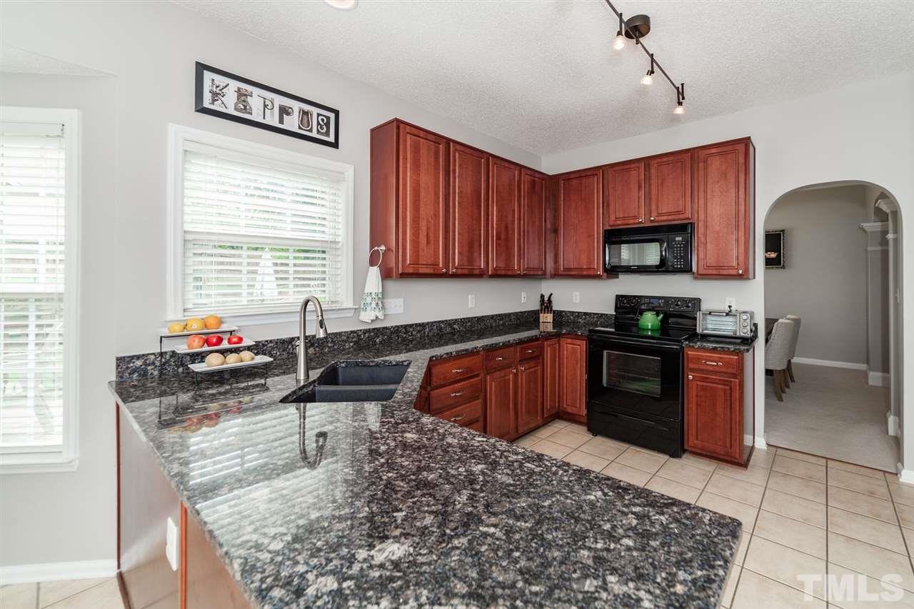 9300 Shallcross Way Raleigh, NC 27617 - Photo 8 of 25 a kitchen with stainless steel appliances granite countertop a stove sink and cabinets