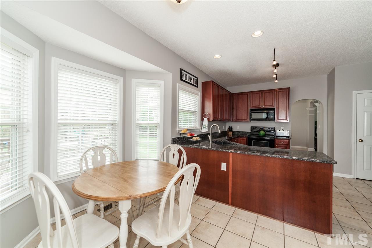 9300 Shallcross Way Raleigh, NC 27617 - Photo 9 of 25 a kitchen with stainless steel appliances kitchen island granite countertop a sink a stove a dining table and chairs
