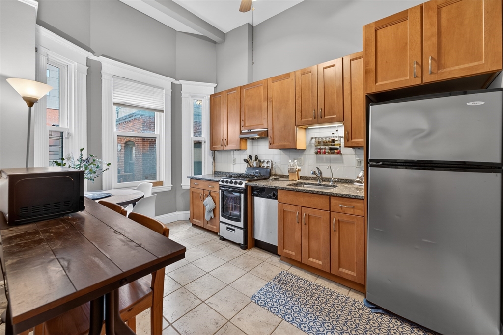 8 Garrison Street, Unit 111 Boston, MA 02116 - Photo 7 of 15 a kitchen with stainless steel appliances granite countertop a refrigerator a sink dishwasher a stove with wooden cabinets and floor