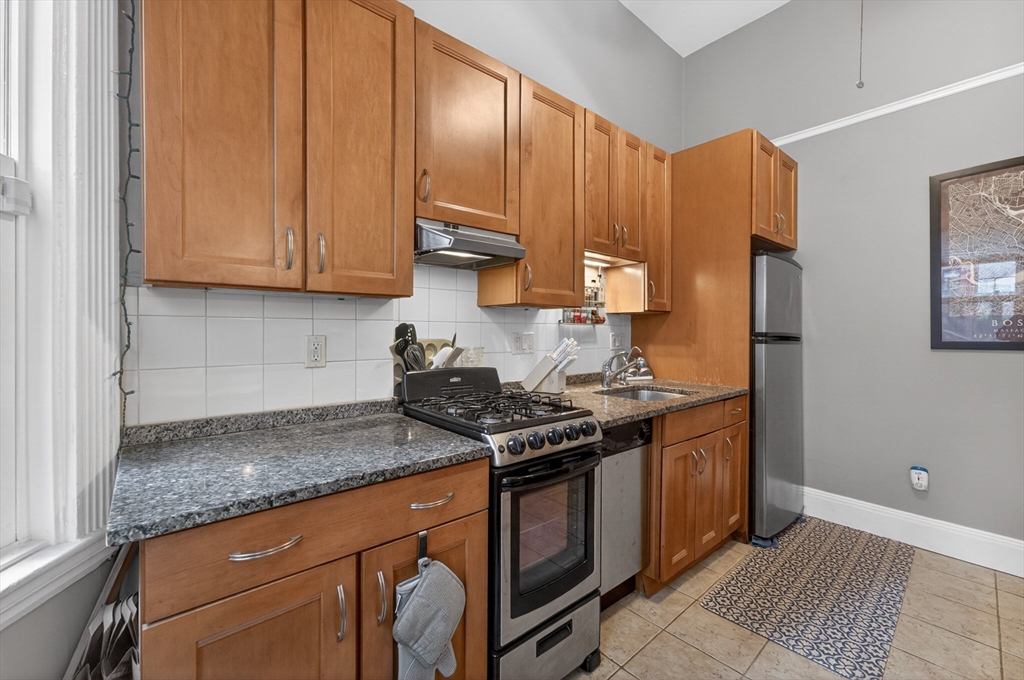 8 Garrison Street, Unit 111 Boston, MA 02116 - Photo 9 of 15 a kitchen with stainless steel appliances granite countertop a stove a refrigerator and wooden cabinets