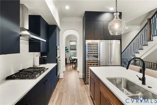 a kitchen with stainless steel appliances kitchen island granite countertop a sink dishwasher and a stove with wooden floor