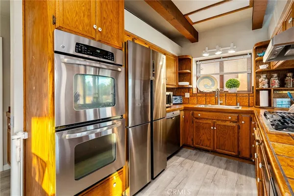 a kitchen with stainless steel appliances granite countertop a refrigerator a stove and a sink with wooden floor